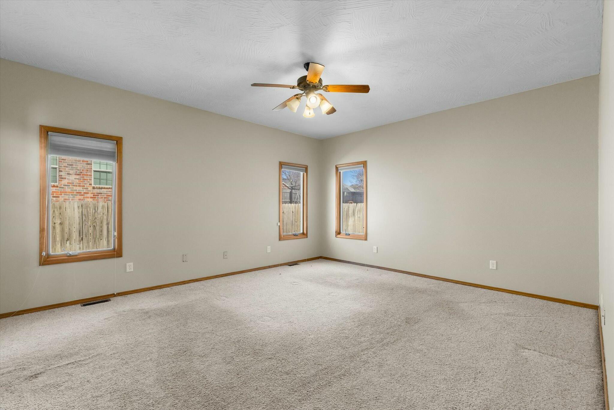 unfurnished room with a textured ceiling, carpet floors, and ceiling fan