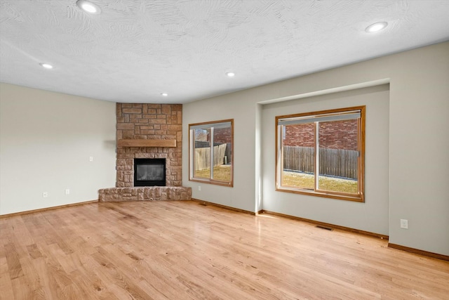 unfurnished living room with a fireplace, light hardwood / wood-style flooring, and a textured ceiling