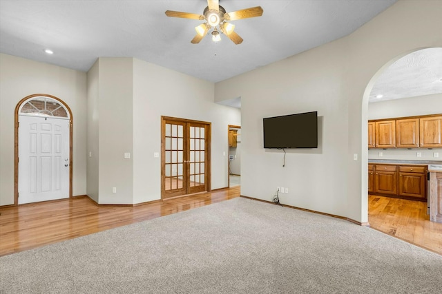 unfurnished living room featuring light carpet, french doors, and ceiling fan