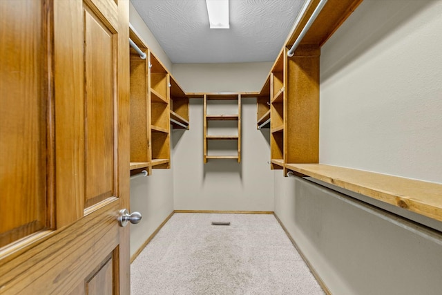 walk in closet featuring light colored carpet