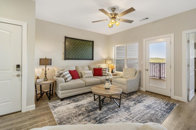 living area with visible vents, baseboards, light wood-style flooring, and a ceiling fan