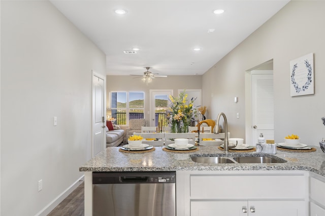 kitchen with visible vents, white cabinets, light stone counters, stainless steel dishwasher, and a sink