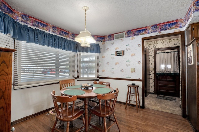 dining room with wood-type flooring and a textured ceiling