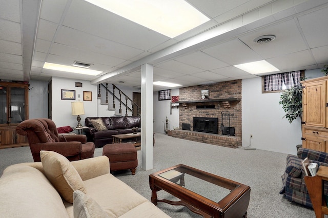 living room featuring a paneled ceiling, light colored carpet, and a brick fireplace