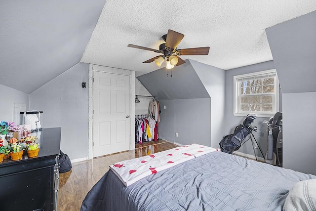 bedroom featuring hardwood / wood-style floors, vaulted ceiling, a textured ceiling, and ceiling fan