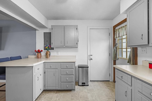 kitchen with gray cabinetry, a breakfast bar, and kitchen peninsula