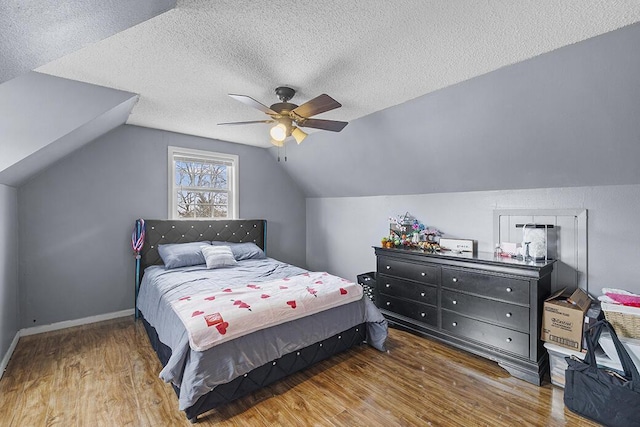 bedroom featuring hardwood / wood-style flooring, ceiling fan, lofted ceiling, and a textured ceiling