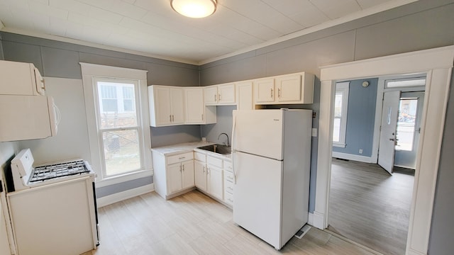 kitchen featuring white appliances, a healthy amount of sunlight, and white cabinets