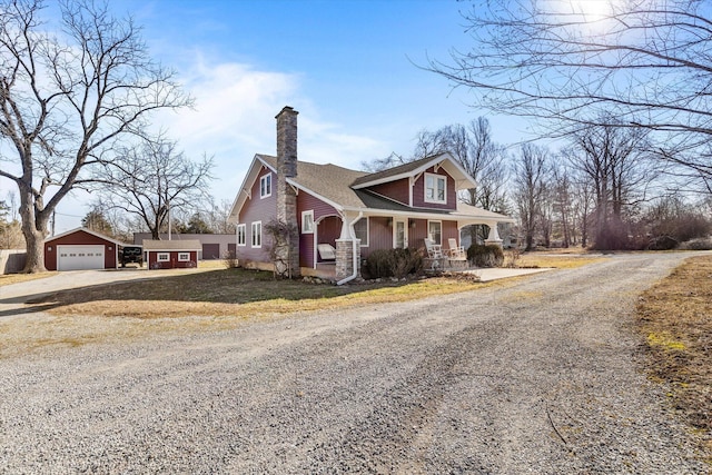 view of front of property featuring a garage, an outdoor structure, and a porch