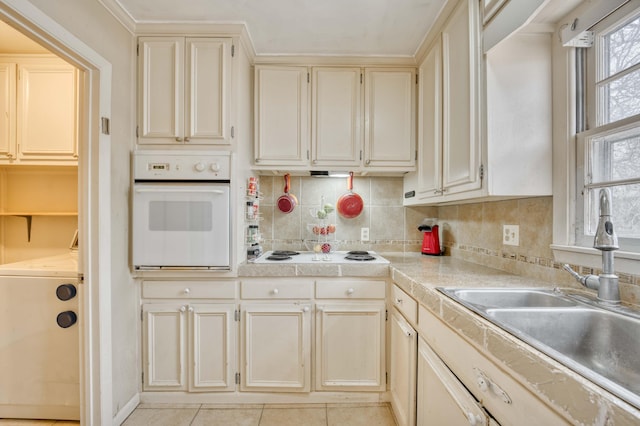 kitchen with tasteful backsplash, washer / dryer, sink, white appliances, and cream cabinetry