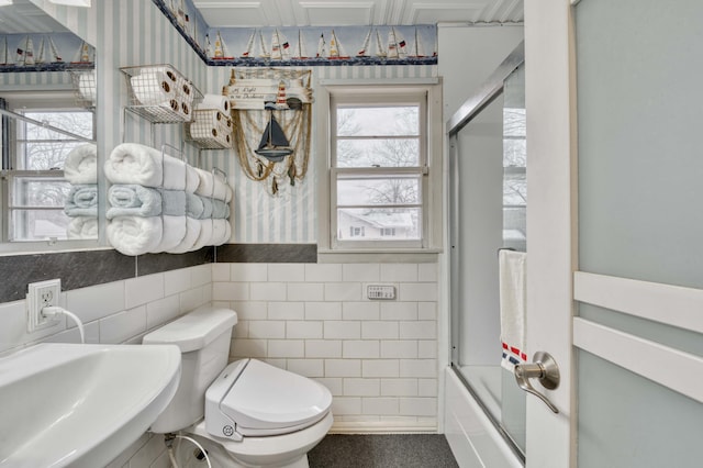 full bathroom with sink, tile walls, shower / bath combination with glass door, and toilet