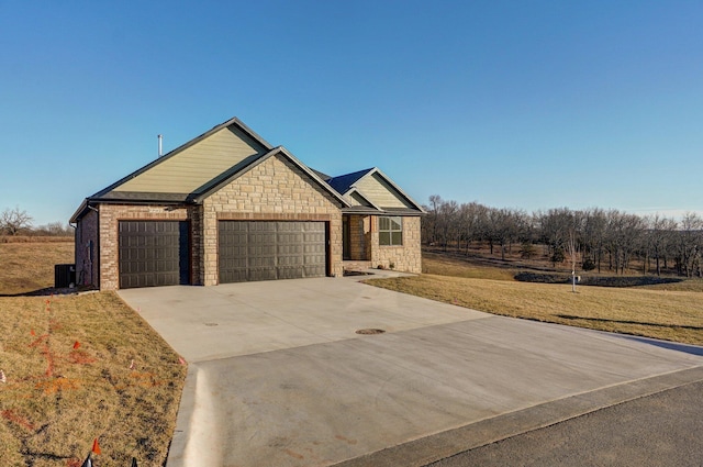 view of front of home featuring an attached garage, central AC unit, concrete driveway, and a front yard