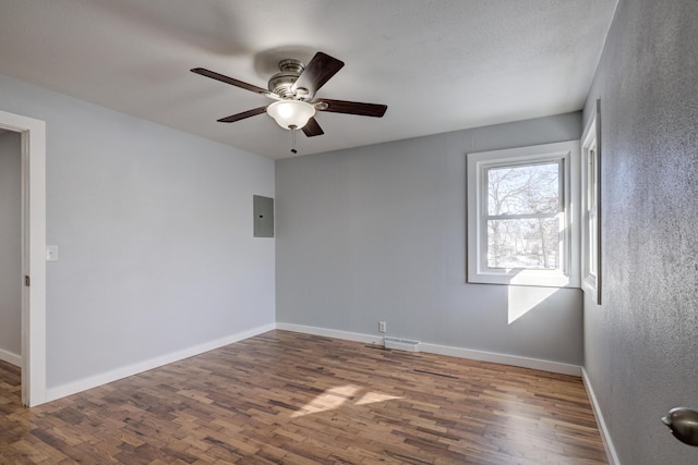 spare room featuring electric panel, dark hardwood / wood-style floors, and ceiling fan