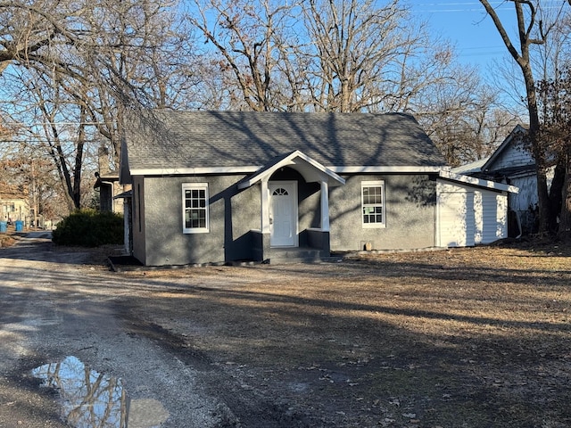 view of front of home with entry steps, driveway, a shingled roof, and stucco siding