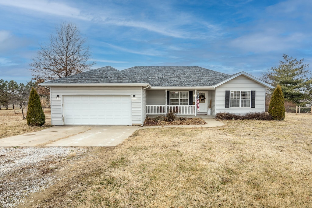 ranch-style home featuring a garage, a porch, and a front lawn