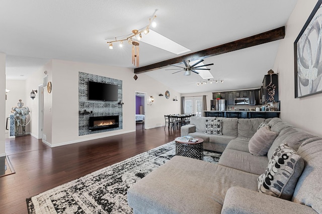living room with lofted ceiling with skylight, dark wood-type flooring, and ceiling fan
