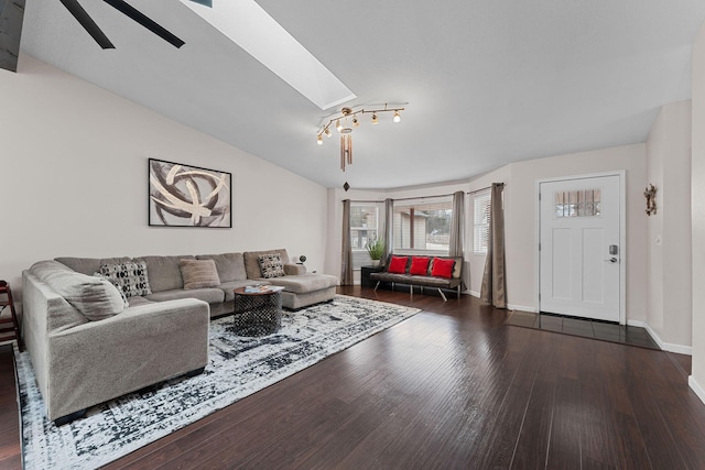 living room featuring dark hardwood / wood-style floors, vaulted ceiling with skylight, and ceiling fan