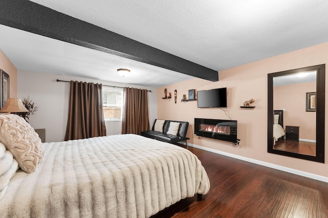 bedroom featuring wood-type flooring, beam ceiling, and a textured ceiling