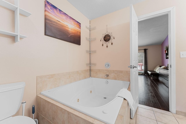 bathroom featuring a relaxing tiled tub, tile patterned floors, and toilet