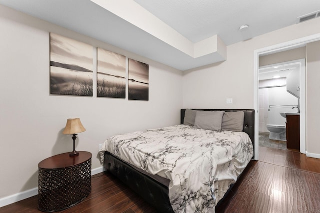 bedroom featuring dark wood-type flooring and ensuite bath