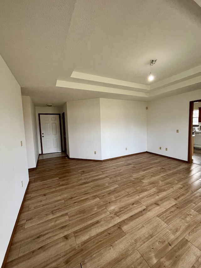 unfurnished room with hardwood / wood-style floors, a textured ceiling, and a tray ceiling