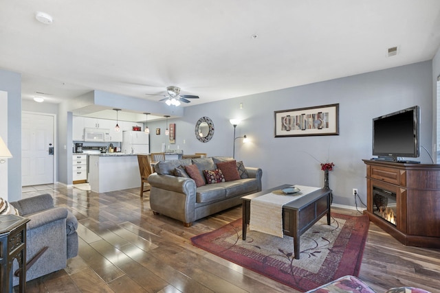 living room featuring dark wood-type flooring and ceiling fan