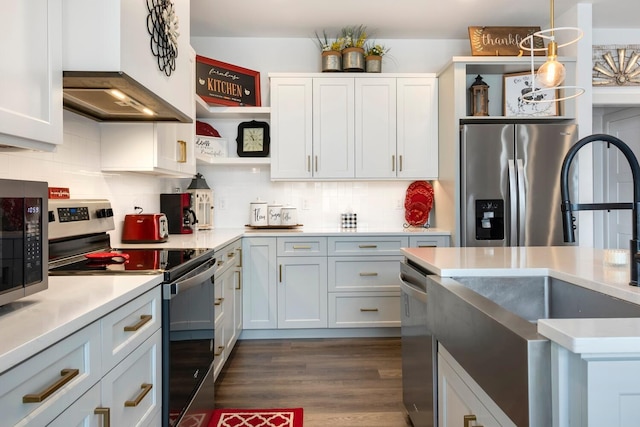 kitchen featuring appliances with stainless steel finishes, decorative backsplash, custom range hood, white cabinets, and decorative light fixtures