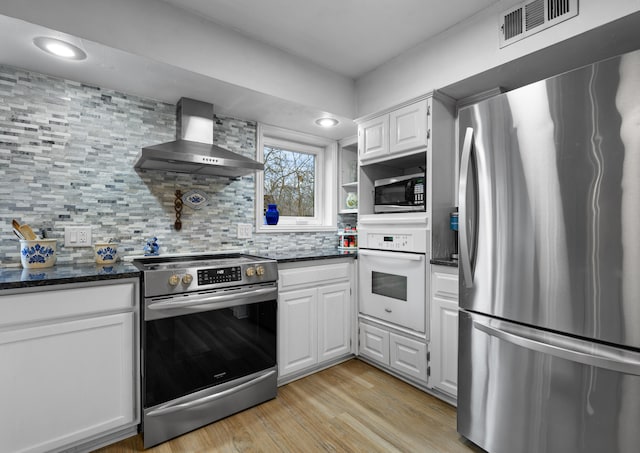 kitchen featuring stainless steel appliances, white cabinetry, light hardwood / wood-style floors, and wall chimney exhaust hood