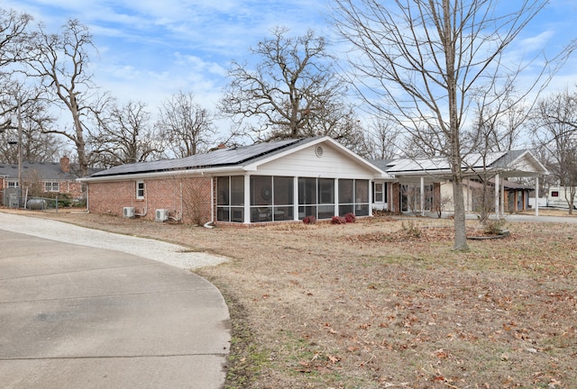 view of front facade with a sunroom and solar panels