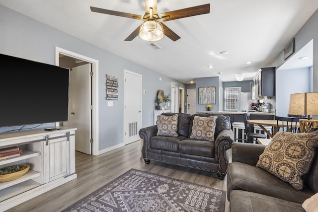 living room featuring ceiling fan and dark hardwood / wood-style floors