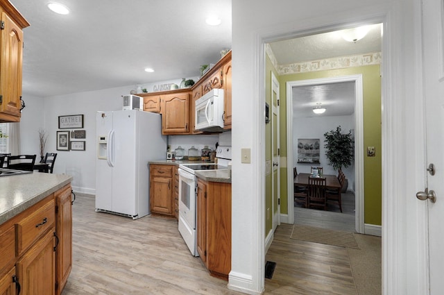 kitchen with white appliances and light hardwood / wood-style floors