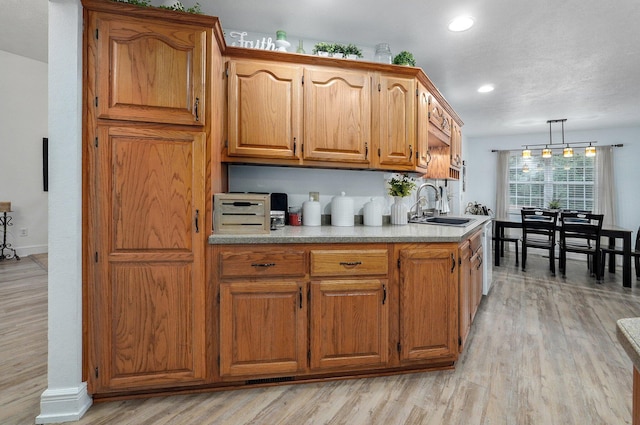 kitchen with sink, light hardwood / wood-style floors, and hanging light fixtures