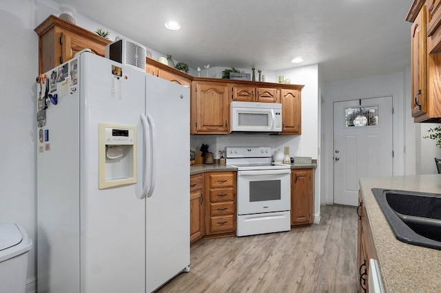 kitchen with white appliances, sink, and light wood-type flooring