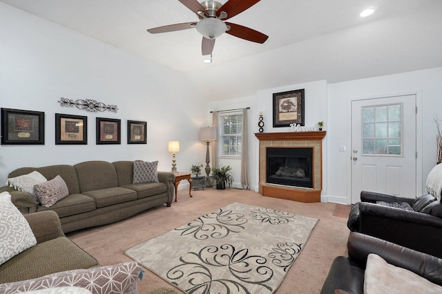 carpeted living room with vaulted ceiling, a tile fireplace, and ceiling fan