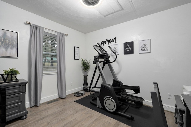 exercise area with a textured ceiling and light hardwood / wood-style floors