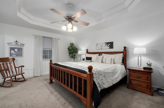 bedroom with a raised ceiling, light carpet, and ceiling fan