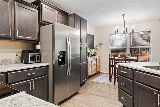 kitchen with light wood-style flooring, stainless steel refrigerator with ice dispenser, a textured ceiling, light countertops, and dark brown cabinets