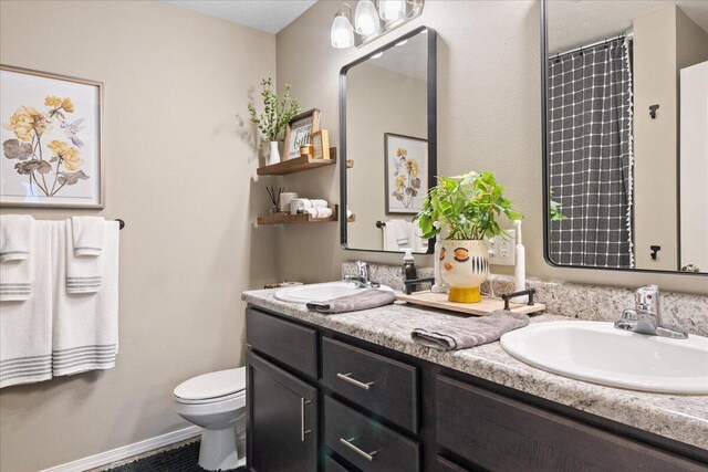 bathroom featuring a sink, toilet, a shower with shower curtain, and double vanity
