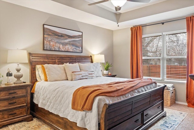 bedroom with light carpet, ceiling fan, a raised ceiling, and baseboards
