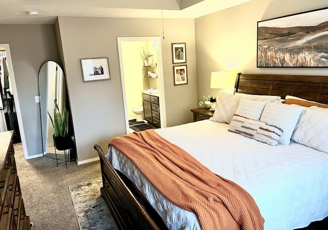 carpeted bedroom featuring ensuite bathroom and baseboards