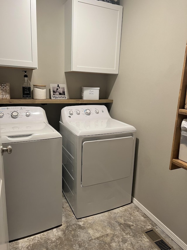laundry room with cabinet space, separate washer and dryer, visible vents, and baseboards
