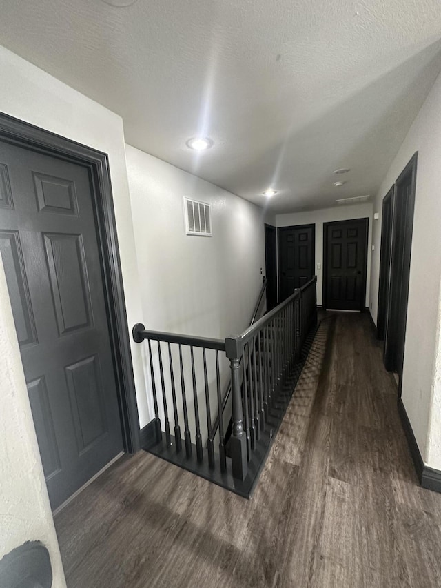 hall featuring dark wood-type flooring and a textured ceiling