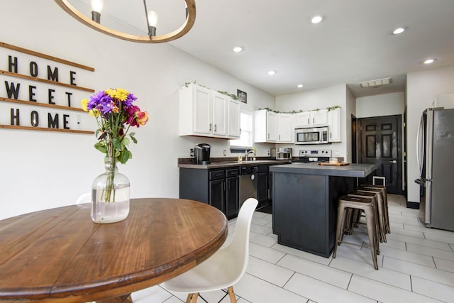 kitchen with white cabinetry, sink, a breakfast bar area, a center island, and stainless steel appliances