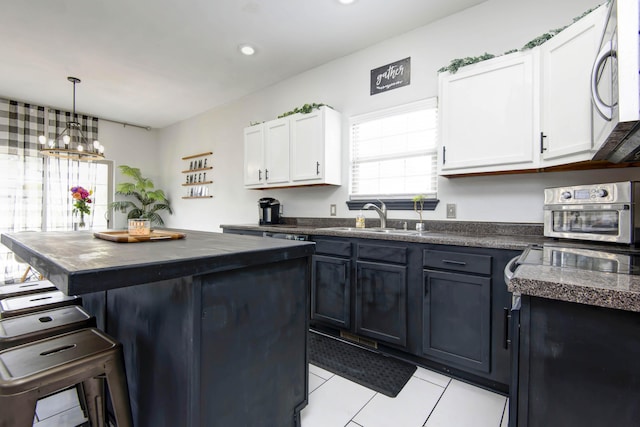 kitchen with sink, white cabinetry, hanging light fixtures, a kitchen island, and a kitchen bar