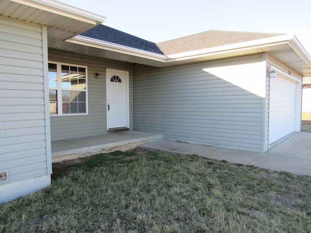 property entrance featuring a shingled roof and an attached garage