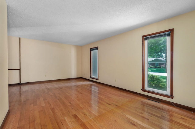 spare room with a textured ceiling and light wood-type flooring