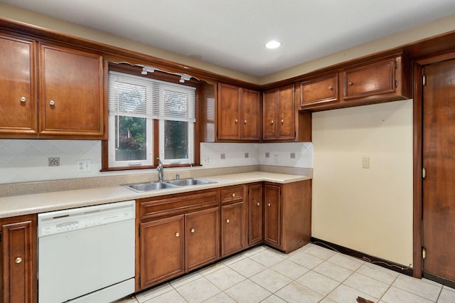 kitchen with white dishwasher, sink, decorative backsplash, and light tile patterned floors