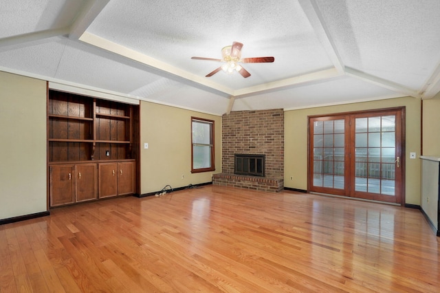 unfurnished living room with lofted ceiling, a fireplace, a textured ceiling, and light wood-type flooring