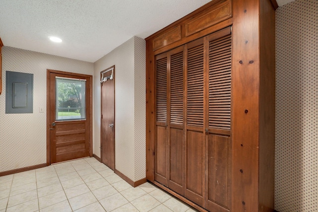 corridor with light tile patterned floors, electric panel, and a textured ceiling