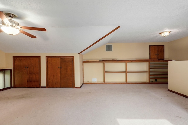 interior space with vaulted ceiling, light colored carpet, a textured ceiling, and ceiling fan